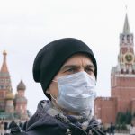 Disease Outbreak, Coronavirus Covid 19 Pandemic, Air Pollution In Moscow, Russia. Portrait Of Adult Man With Medical Protective Mask On Face With Kremlin And Red Square On Background.